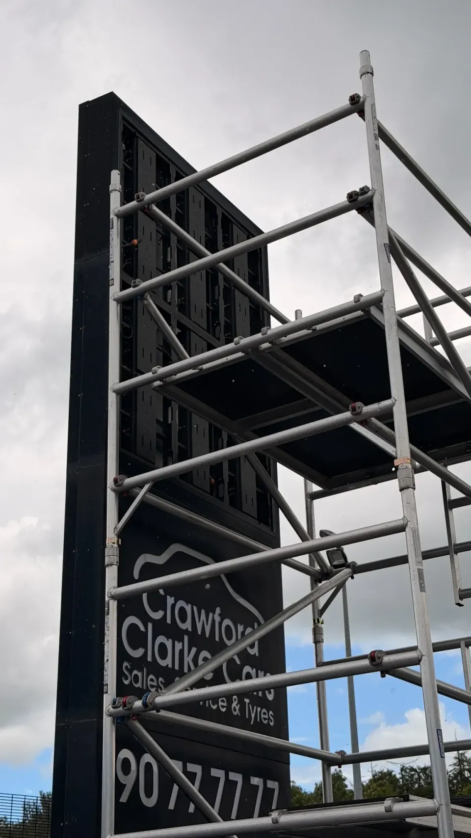 Scaffolding around the raised sign structure at Crawford Clarke Cars