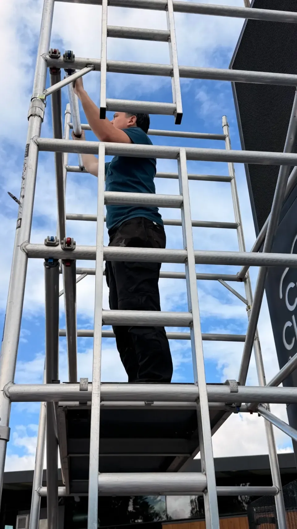 Installer working from scaffolding on the Crawford Clarke LED totem