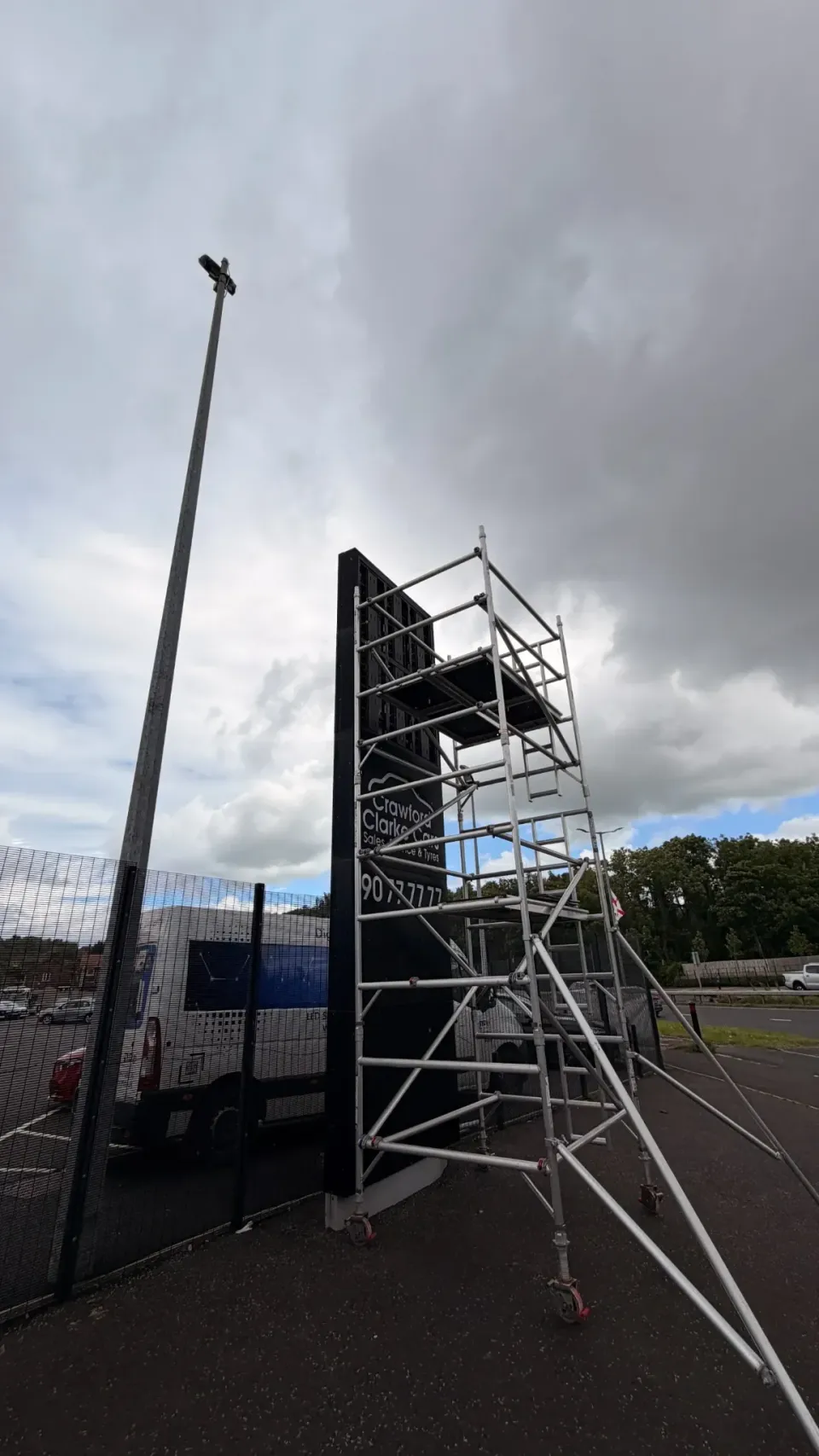 Wide view of the Crawford Clarke roadside sign and access scaffold during installation